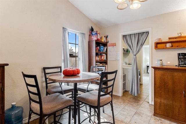 tiled dining room featuring lofted ceiling and independent washer and dryer