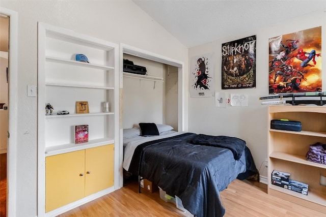 bedroom with vaulted ceiling, wood-type flooring, and a closet