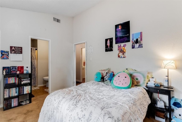 bedroom featuring carpet flooring, ensuite bathroom, and vaulted ceiling