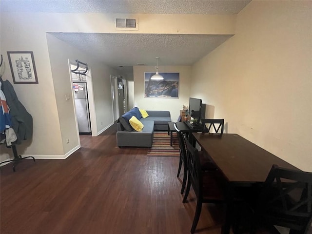 dining space with dark hardwood / wood-style flooring and a textured ceiling