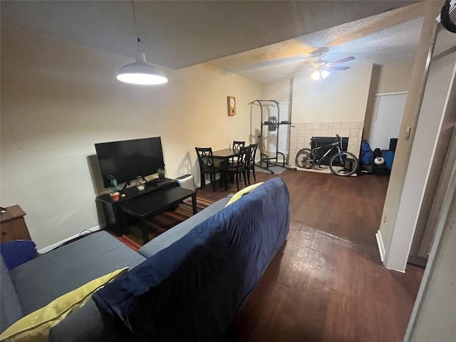 living room featuring ceiling fan, dark hardwood / wood-style flooring, and a textured ceiling