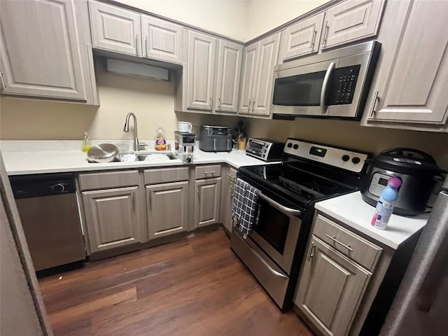 kitchen featuring appliances with stainless steel finishes, dark hardwood / wood-style flooring, gray cabinets, and sink