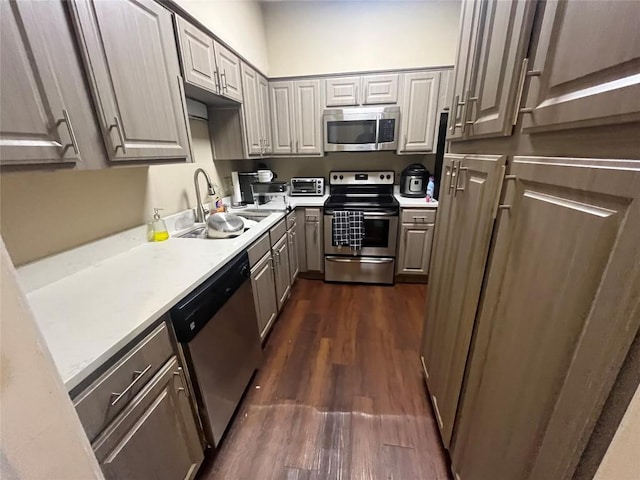 kitchen with gray cabinetry, sink, appliances with stainless steel finishes, and dark wood-type flooring