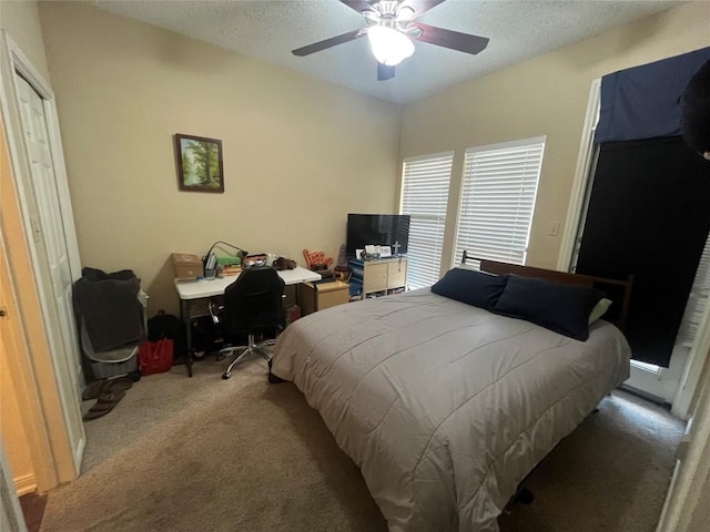 carpeted bedroom featuring ceiling fan and a textured ceiling