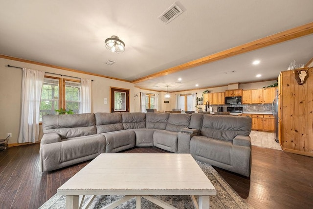 living room featuring beam ceiling, crown molding, and dark wood-type flooring