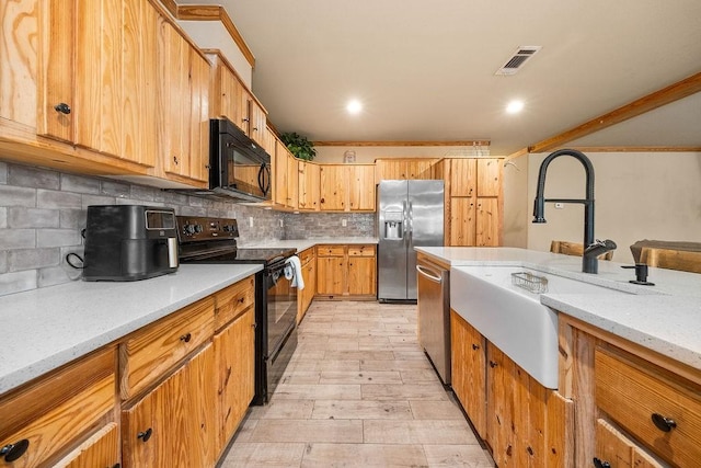 kitchen featuring backsplash, black appliances, sink, light wood-type flooring, and light stone countertops