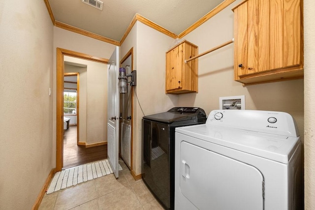 laundry area with cabinets, independent washer and dryer, ornamental molding, and light tile patterned floors