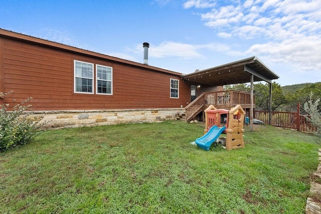 rear view of house featuring a yard, a playground, and a deck