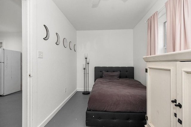 bedroom featuring ceiling fan, white fridge, and concrete flooring