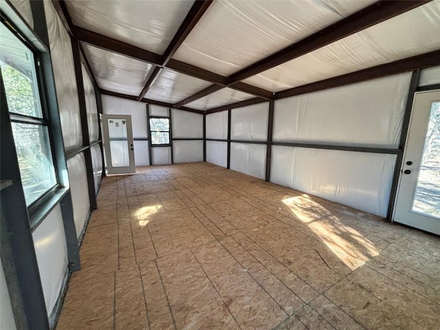 unfurnished sunroom with lofted ceiling with beams and a healthy amount of sunlight