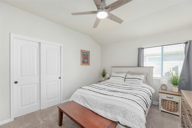 bedroom with ceiling fan, light colored carpet, lofted ceiling, and a closet