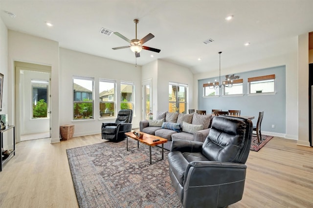 living room with ceiling fan with notable chandelier, light hardwood / wood-style floors, and plenty of natural light