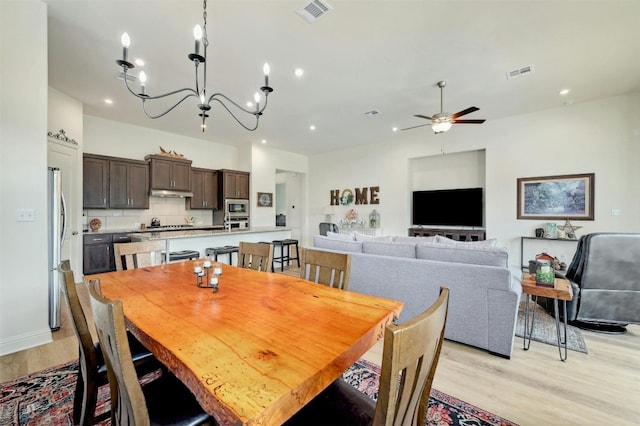 dining area featuring ceiling fan with notable chandelier and light hardwood / wood-style flooring