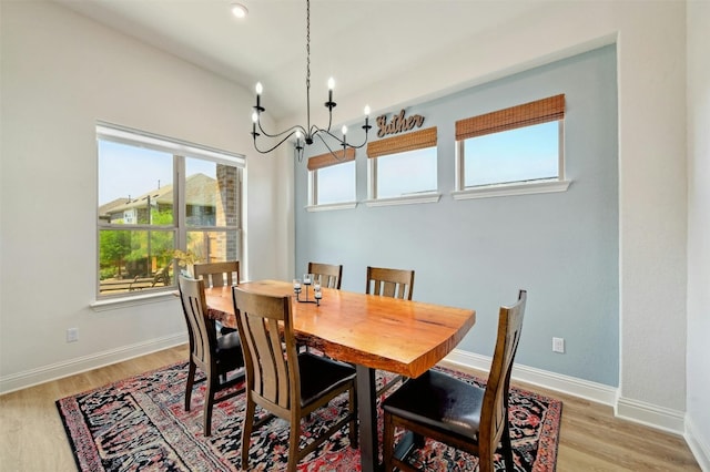 dining area with light hardwood / wood-style floors and a notable chandelier