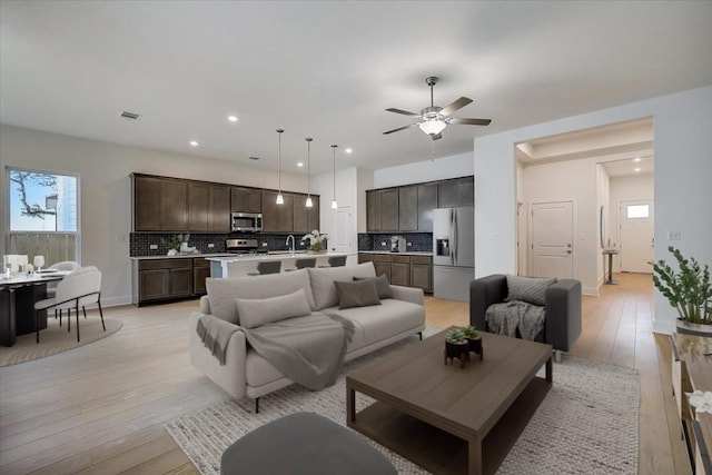 living room featuring light hardwood / wood-style flooring, ceiling fan, and sink