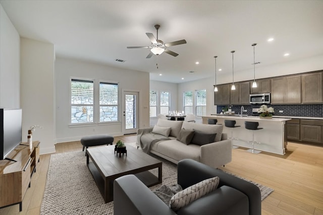 living room featuring light hardwood / wood-style floors, ceiling fan, and sink