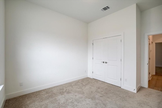 unfurnished bedroom with light carpet and a closet