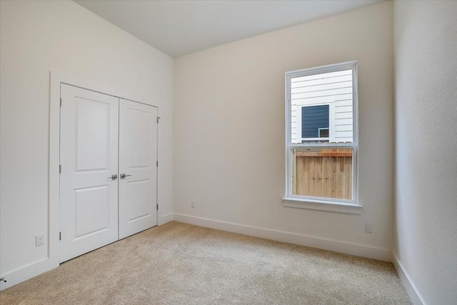 unfurnished bedroom featuring light colored carpet and a closet