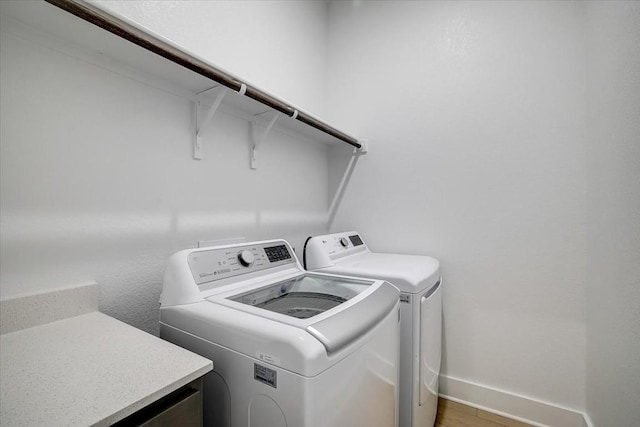 clothes washing area with hardwood / wood-style flooring and independent washer and dryer