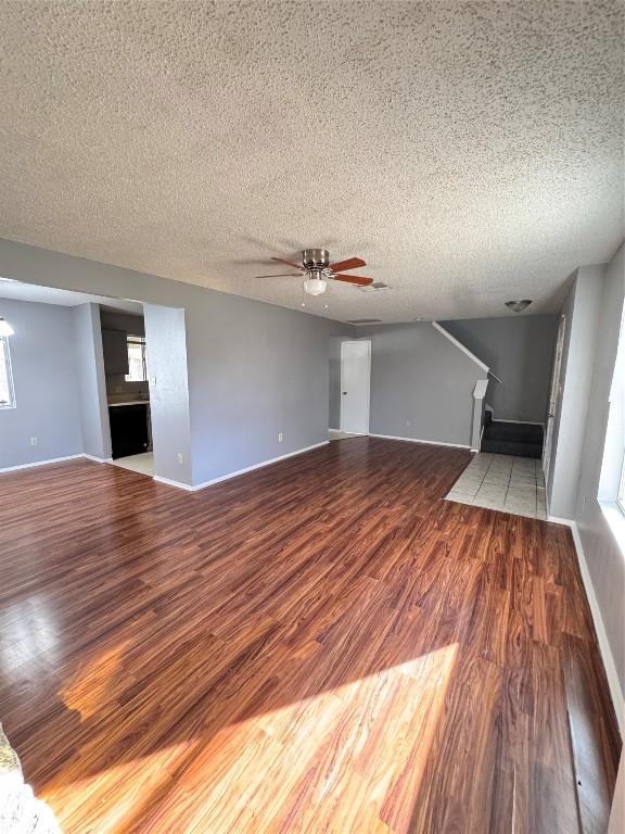 unfurnished living room with hardwood / wood-style flooring, ceiling fan, and a textured ceiling