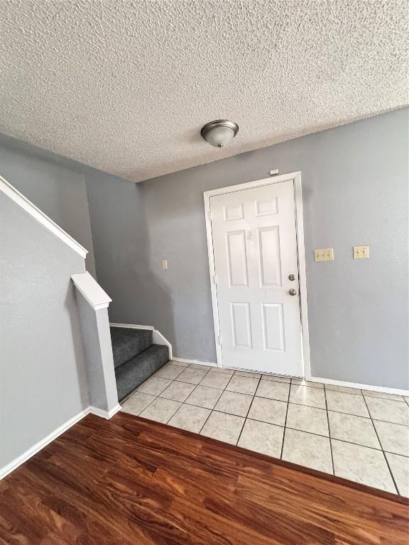 foyer entrance with light tile patterned floors and a textured ceiling