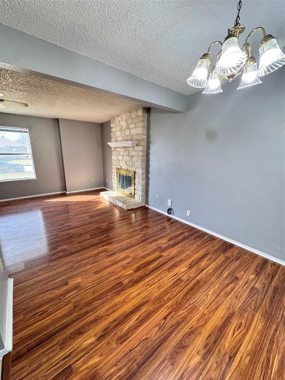 unfurnished living room featuring a fireplace, hardwood / wood-style floors, a textured ceiling, and a notable chandelier