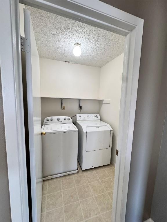 laundry room with washing machine and dryer and a textured ceiling