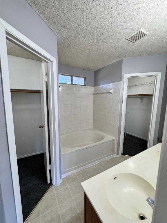 bathroom featuring a textured ceiling, vanity, and a tub