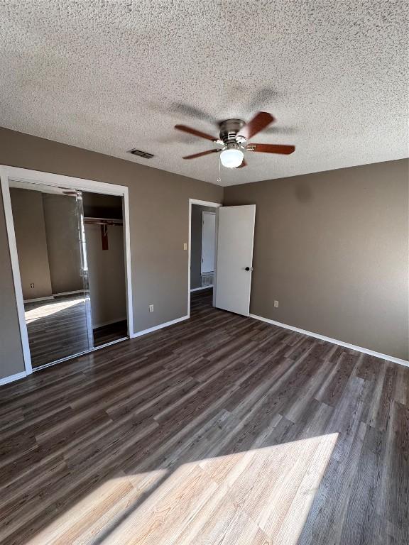 unfurnished bedroom with ceiling fan, dark hardwood / wood-style flooring, a textured ceiling, and a closet