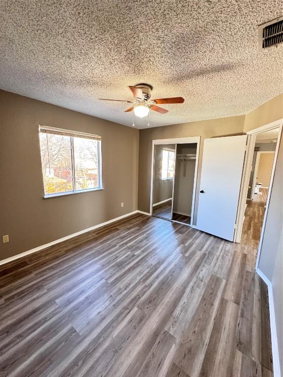 unfurnished bedroom featuring dark hardwood / wood-style flooring, ceiling fan, a closet, and a textured ceiling