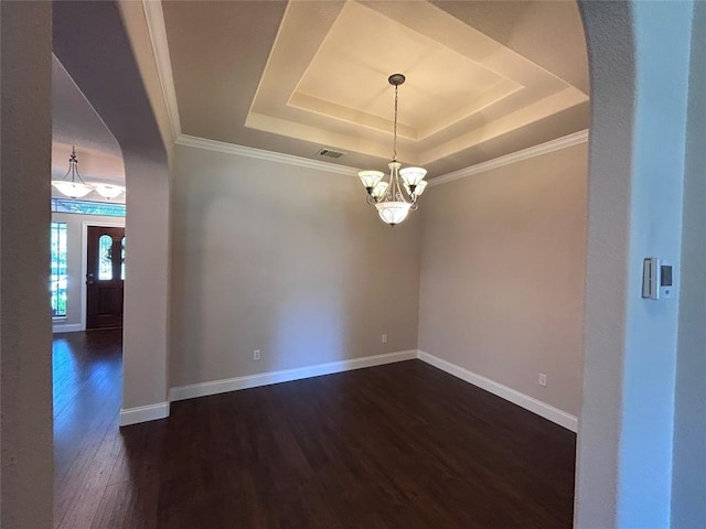 unfurnished room with a raised ceiling, ornamental molding, dark wood-type flooring, and a chandelier