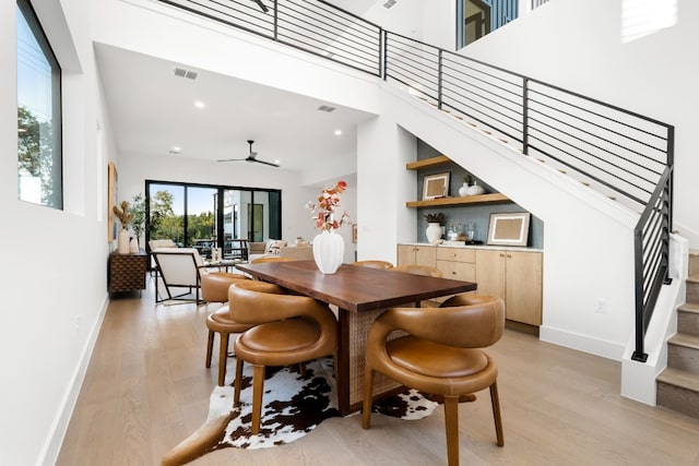 dining area featuring a towering ceiling, light hardwood / wood-style flooring, and ceiling fan