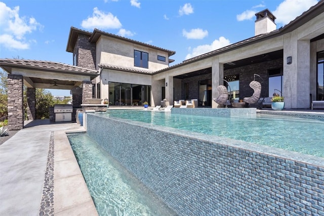 view of pool with a grill, a patio, and an outdoor kitchen