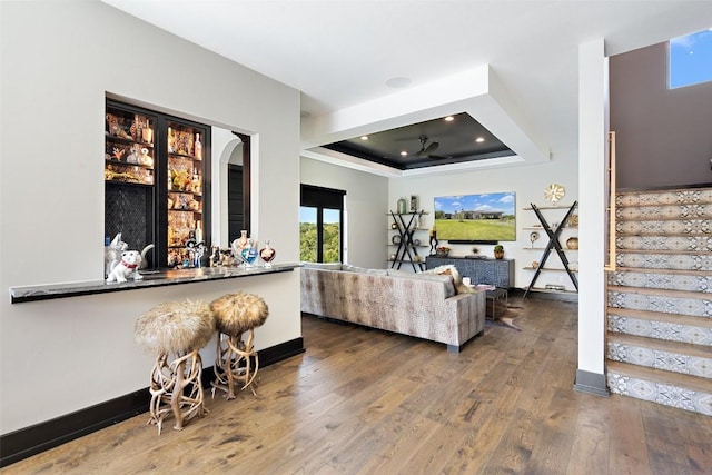 living room with a raised ceiling and hardwood / wood-style floors