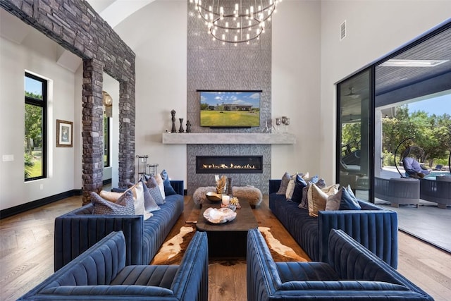 19204 Secretariat Pl, Spicewood, TX 78669 - living room featuring a towering ceiling, a chandelier, a glass covered fireplace, and wood finished floors