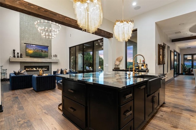 19204 Secretariat Pl, Spicewood, TX 78669 - kitchen featuring dark cabinetry, wood finished floors, a chandelier, dark stone countertops, and open floor plan