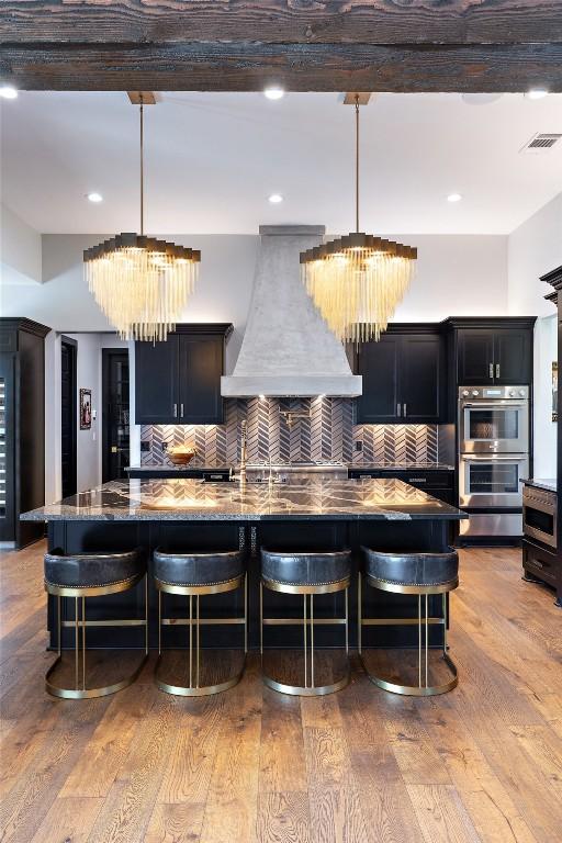 19204 Secretariat Pl, Spicewood, TX 78669 - kitchen featuring a chandelier, premium range hood, stainless steel double oven, decorative backsplash, and recessed lighting