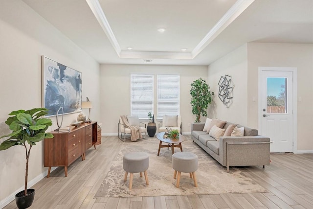 living room with a raised ceiling, plenty of natural light, ornamental molding, and light wood-type flooring