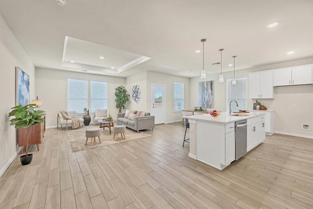 kitchen featuring a kitchen island with sink, dishwasher, white cabinets, and pendant lighting