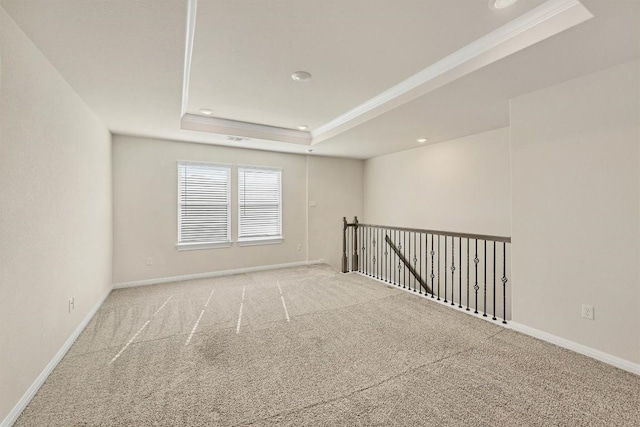 carpeted spare room featuring a tray ceiling