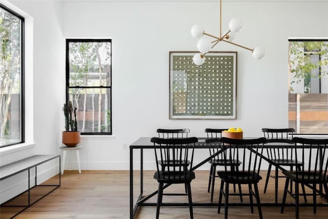 dining area with a notable chandelier, plenty of natural light, and light wood-type flooring