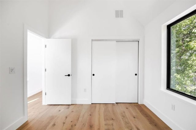 unfurnished bedroom with a closet, light hardwood / wood-style floors, and multiple windows