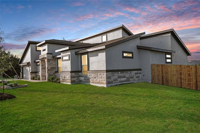 property exterior at dusk featuring a lawn