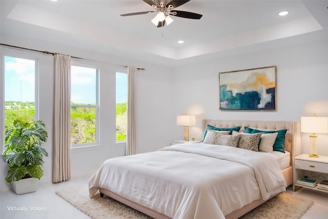 bedroom with ceiling fan, a raised ceiling, and multiple windows