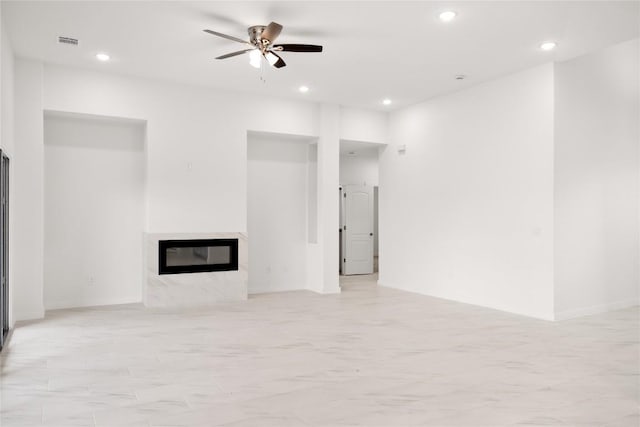 unfurnished living room with ceiling fan and a high end fireplace