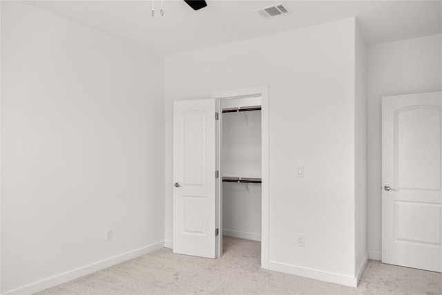 unfurnished bedroom with light colored carpet, a closet, and ceiling fan