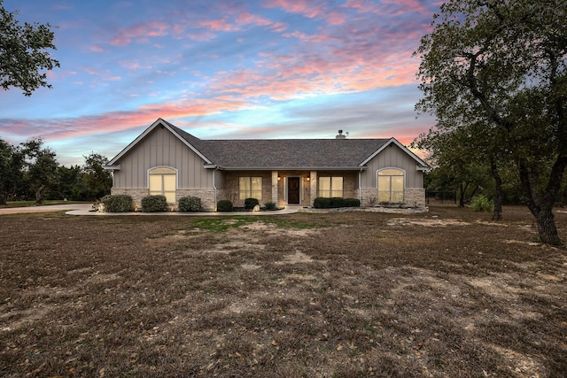 ranch-style home featuring stone siding, a shingled roof, and board and batten siding