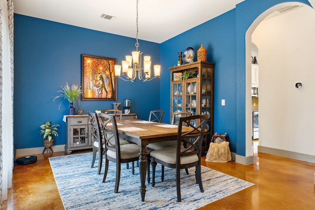 dining area featuring arched walkways, visible vents, finished concrete floors, a chandelier, and baseboards