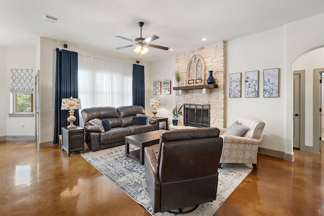 living room with arched walkways, visible vents, plenty of natural light, and a stone fireplace