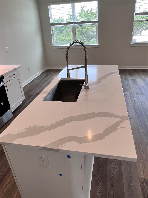 12001 Vista Parke Dr Unit 1202, Austin, TX 78726 - kitchen view of light stone counters, white cabinetry, dark wood-type flooring, electric stove, and a center island with sink